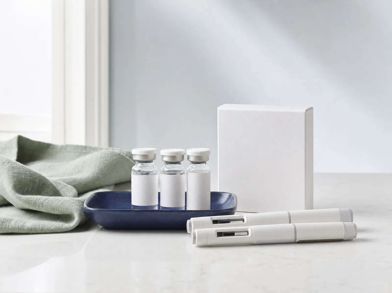 Injectable vials, pen injectors and a medicine box on a quartz counter