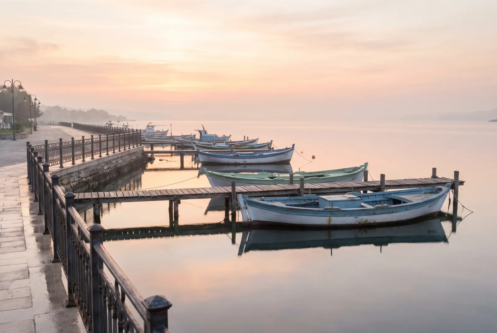 Small boats moored at wooden piers on a calm bay at sunrise.